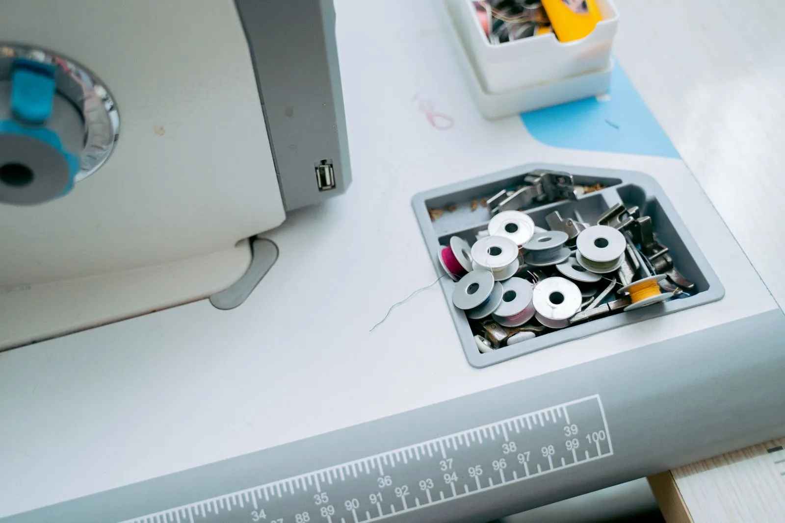 Detailed view of a sewing machine with spools and tools in a tailor workshop.